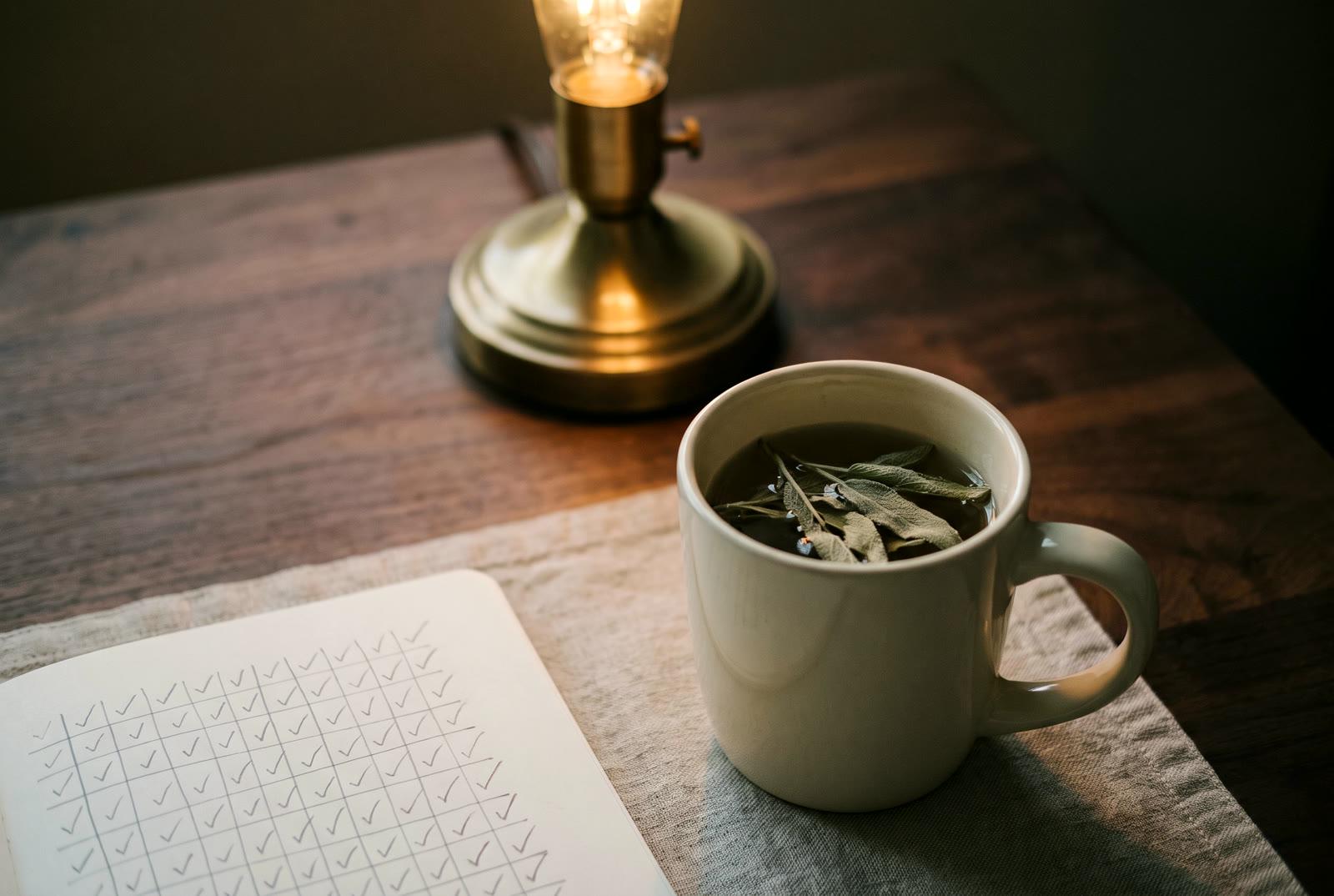 An evening table under warm lamp light, the week’s tracker sheet filled in softly out of focus